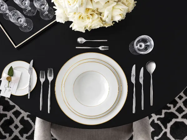Tischgedeck mit Geschirr der Kollektion 'Anmut' von Villeroy & Boch, elegant arrangiert auf einem schwarzen Tisch.