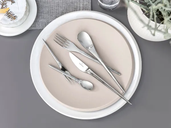 Villeroy & Boch NewMoon table cutlery on a beige plate on a grey background.