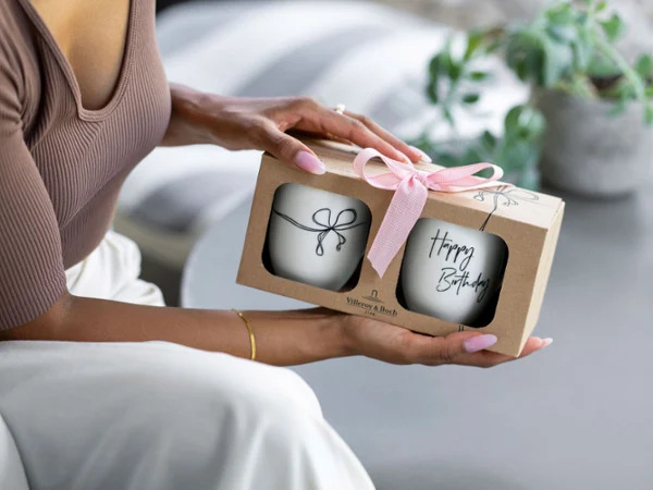 ‘Happy Birthday' mug in a gift box with a bow Person holding a gift box with a pink bow containing two 'Happy Birthday' Statement mugs.