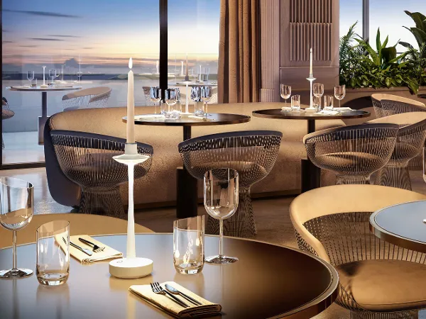 Elegantes Restaurant-Interieur mit gedeckten Tischen, modernen Stühlen, großen Fenstern und Blick auf das Wasser bei Sonnenuntergang.