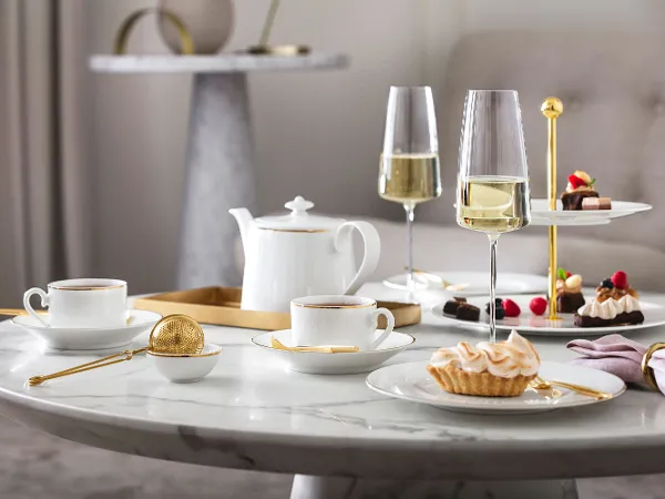 Elegant afternoon tea setting with desserts and champagne on a marble table, served on Château Septfontaines crockery and in MetroChic glasses.