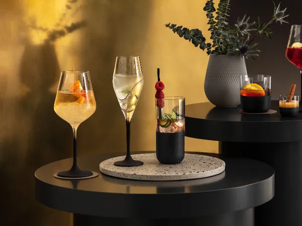Różne koktajle, elegancko zaprezentowane w kieliszkach i szklankach Manufacture na nowoczesnym stole barowym z nastrojowym oświetleniem.