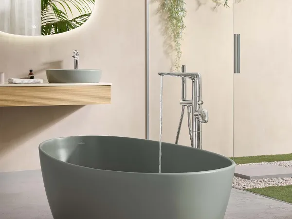 An open-plan bathroom in a natural style with a freestanding oval green bath.