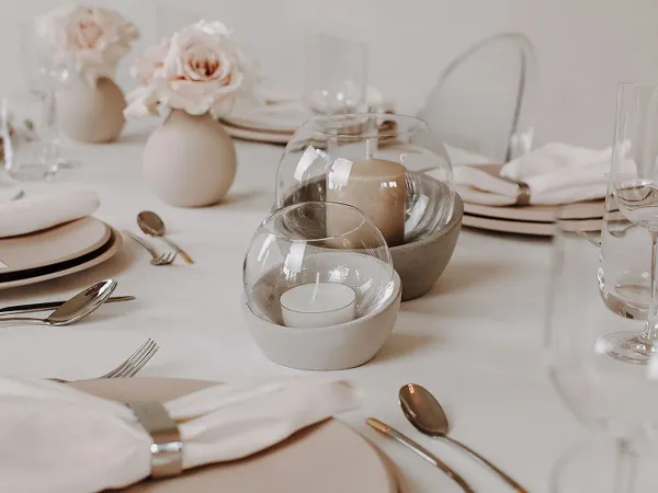 Un portacandela NewMoon come elemento decorativo su una tavola apparecchiata per una cena in compagnia.