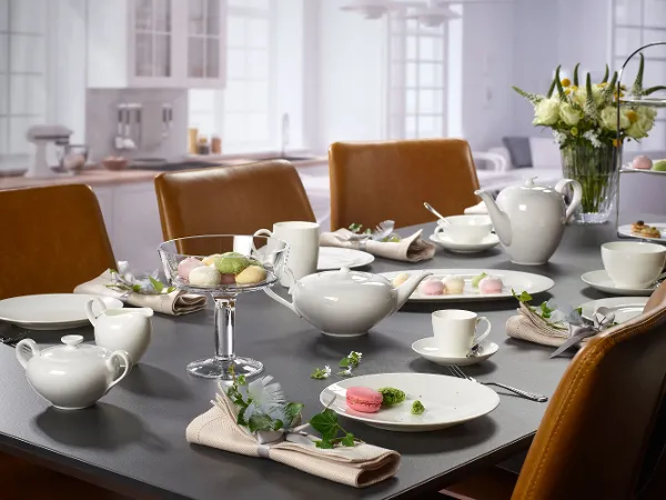 Tischgedeck mit der Kollektion 'Anmut' von Villeroy & Boch, bestehend aus Porzellan-Geschirr, Gläsern und Dekoration mit Blumen und Macarons.