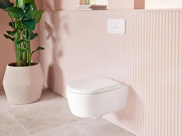 Miska WC wisząca z kolekcji łazienkowej Skyla firmy Villeroy & Boch Miska WC wisząca z kolekcji łazienkowej Skyla firmy Villeroy & Boch w kolorze Stone White (biały mat), w komplecie z białą płytką uruchamiającą ViConnect, prezentowana jest w stylowo urządzonym wnętrzu łazienki w pastelowych odcieniach, obok rośliny doniczkowej.