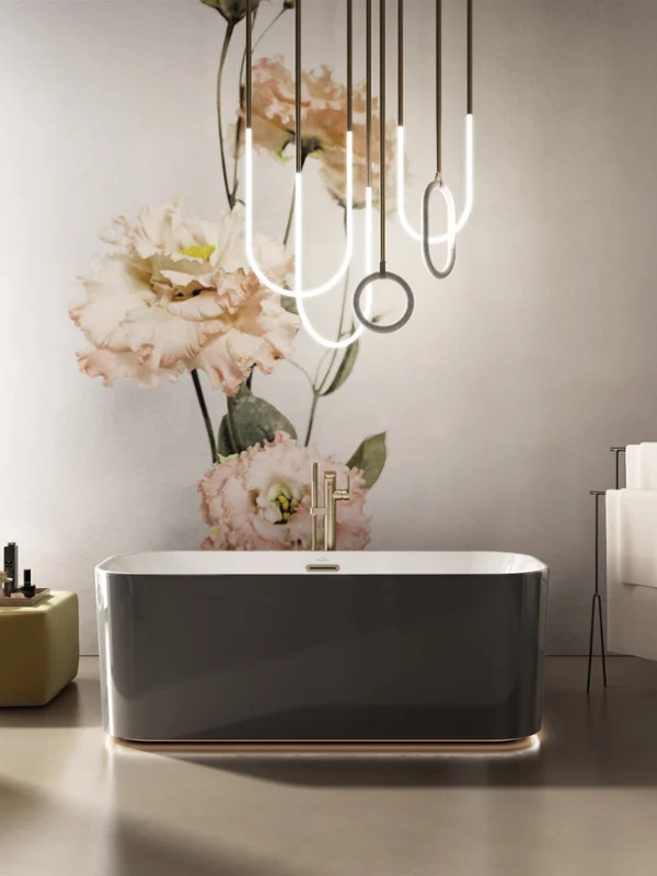 Freestanding black bath with a gold tap from the Finion collection A modern bathroom with an elegant freestanding Finion bath, modern lights and a large wall painting with a floral theme in the background.
