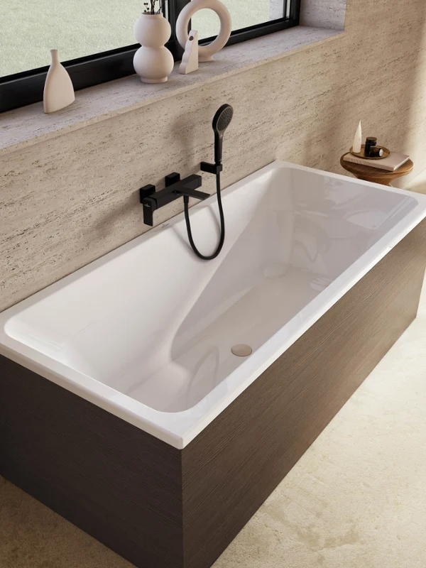 Avento bath with a black wall-mounted tap, a hand shower and dark wood panelling Modern rectangular Avento bath with dark wood panelling, a black wall-mounted tap and a hand shower. The bath is standing next to a large window with decorative objects on the windowsill.