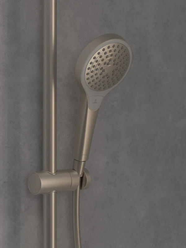 Un gros plan sur une pomme de douchette à main moderne en chrome, montée sur une barre réglable verticalement devant un mur carrelé gris.