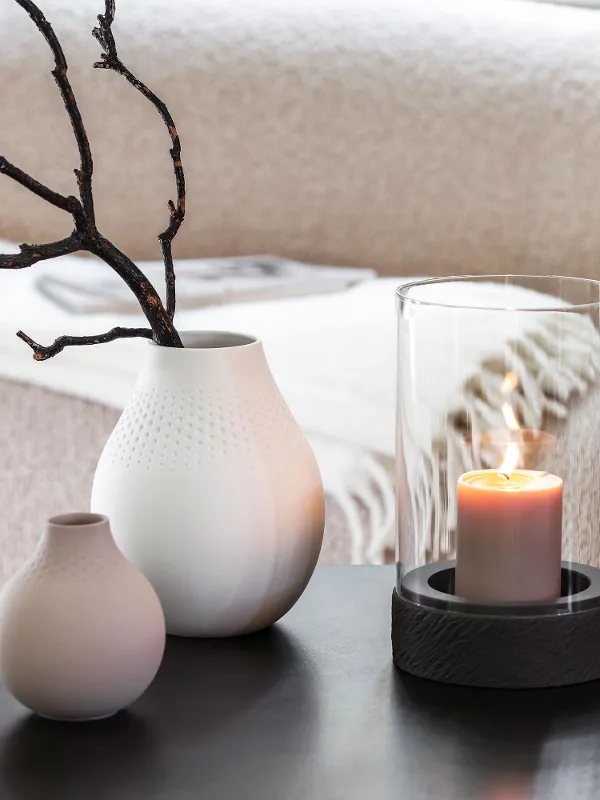 A Manufacture candle standing on a table next to two Manufacture vases.