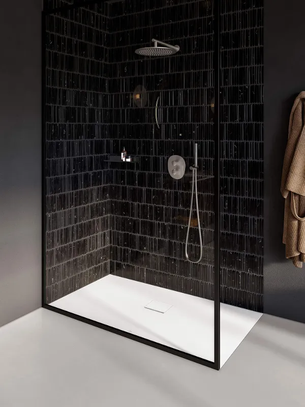 Modern walk-in shower with a glass screen, stainless steel taps from the Antao collection on black Metro tiles.