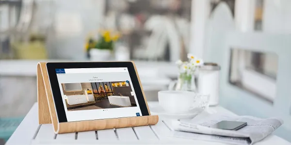 A tablet on a wooden stand displays interior fittings from Villeroy & Boch as well as a cup, a saucer, a smartphone and the ‘Download brochures’ service.