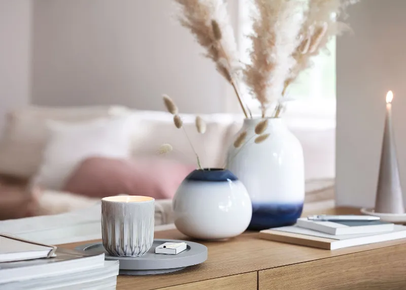 A living room with white and blue Lave vases, books and a Perlemor scented candle.