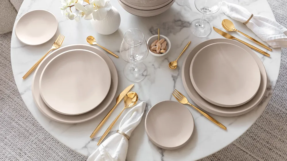 Table set with NewMoon tableware and gold MetroChic cutlery A table set with Villeroy & Boch beige NewMoon plates and gold MetroChic cutlery