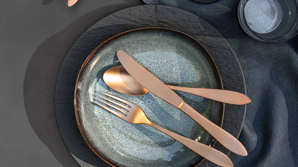 Manufacture cutlery with two Lave plates Elegant table decoration with two Lave plates, Manufacture cutlery, a bowl of olives and a glass of white wine on a grey tablecloth.