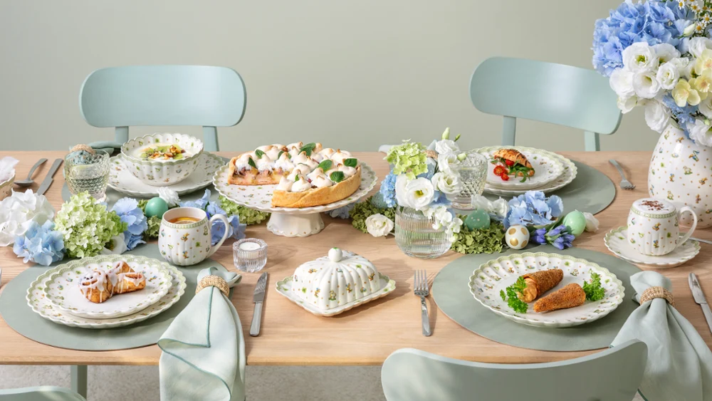 A Easter Delight dining table set for four with Easter Delight decorations, pastel tableware, and plates of food arranged neatly.