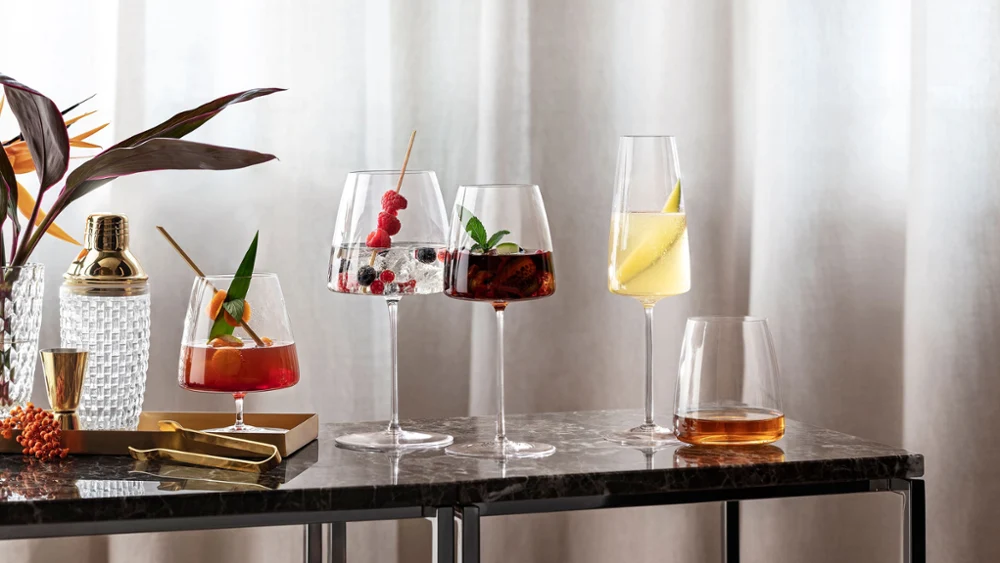 Verschillende cocktails in elegante MetroChic glazen op een marmeren tafel naast een plant.