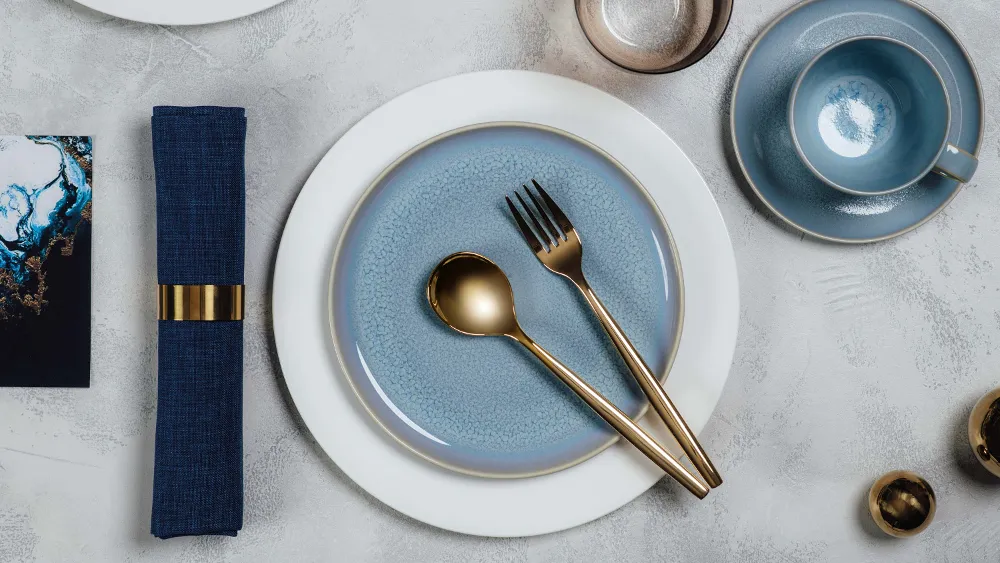 Elegant table decoration with blue Crafted crockery and white Royal crockery, gold MetroChic cutlery and a matching napkin.