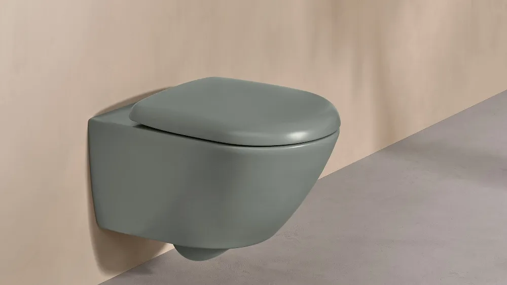 A Villeroy & Boch toilet from the Antao collection in green with a white control panel on a natural-coloured wall.