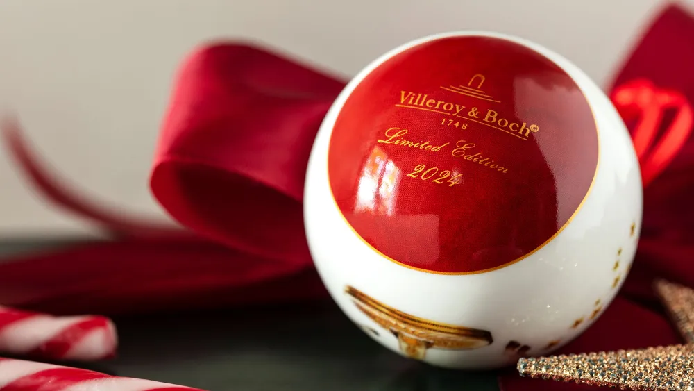 Close-up of an ornament & Villeroy & Boch from the 2024 limited edition collection, showing a red and white design with candy canes, and a red bow in the background.