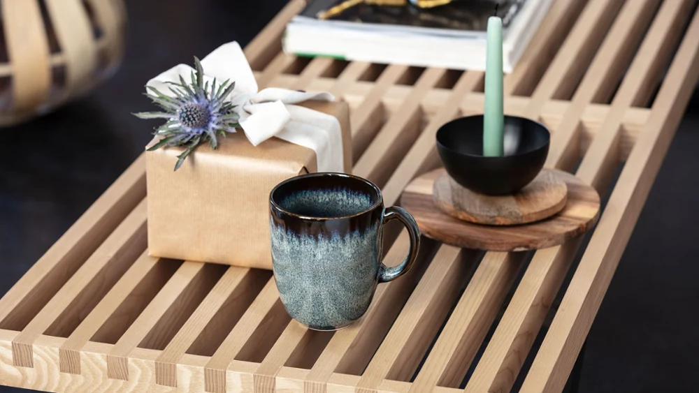Lave beker, cadeaudoos met strik en schaal op houten dienblad, op elegante tafel.
