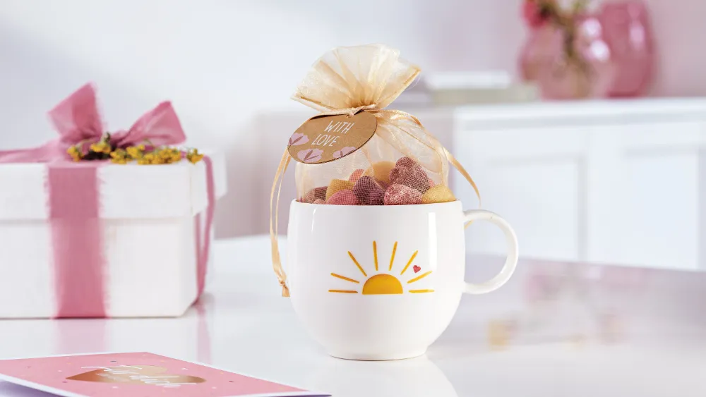 With Love cup with a yellow sun and heart pattern prepared as a gift with sweets.