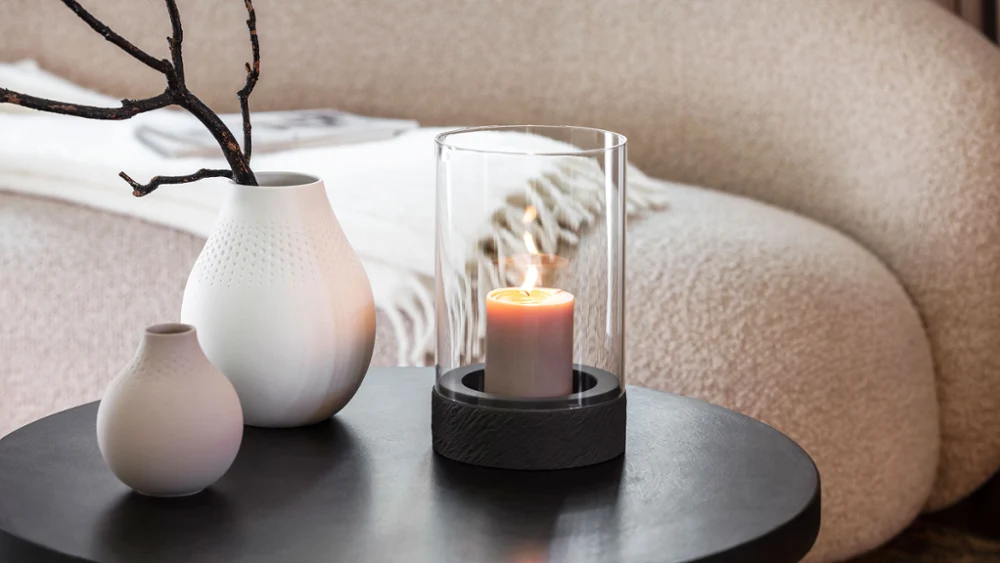 A Manufacture candle standing on a table next to two Manufacture vases.