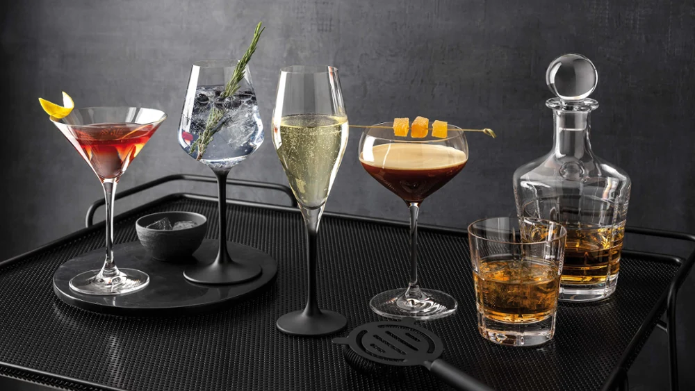 Een zwart dienblad met verschillende drankjes in Manufacture glazen en een Ardmore whiskykaraf erop.