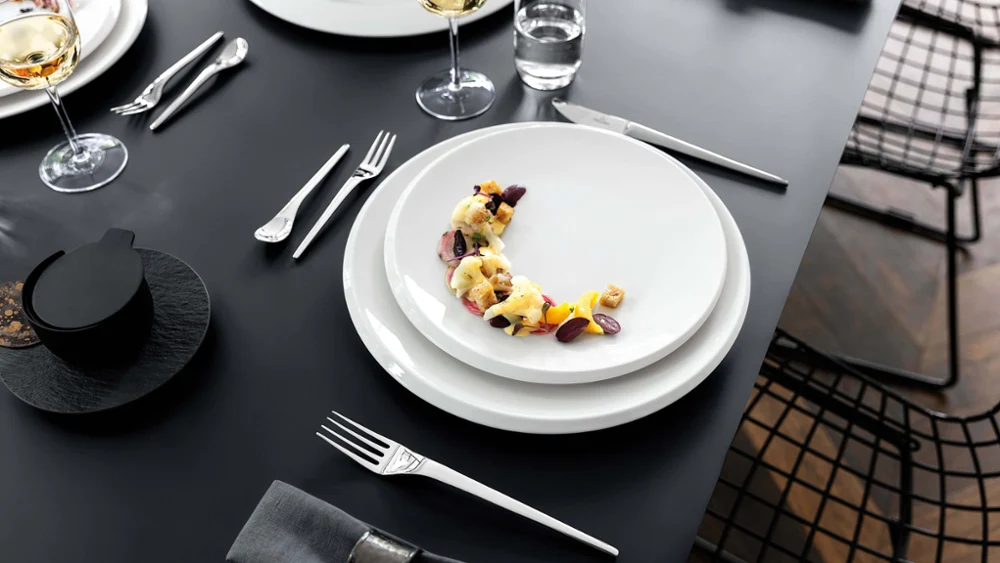 Elegant gedekte eettafel met NewMoon borden en wijnglazen.