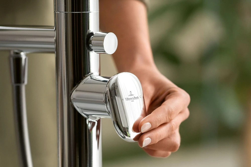 La mano di una donna aziona il rubinetto di design della collezione Antao di Villeroy & Boch.