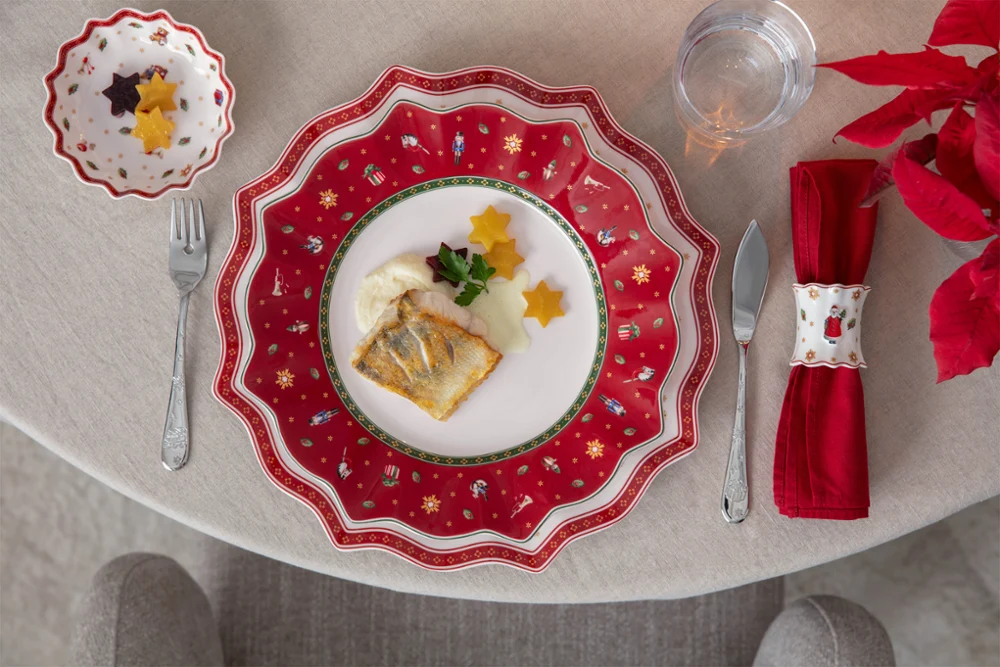 A decorative festive plate A decorative festive plate featuring fish, sauce, parsley and star-shaped vegetables on a festively laid table.