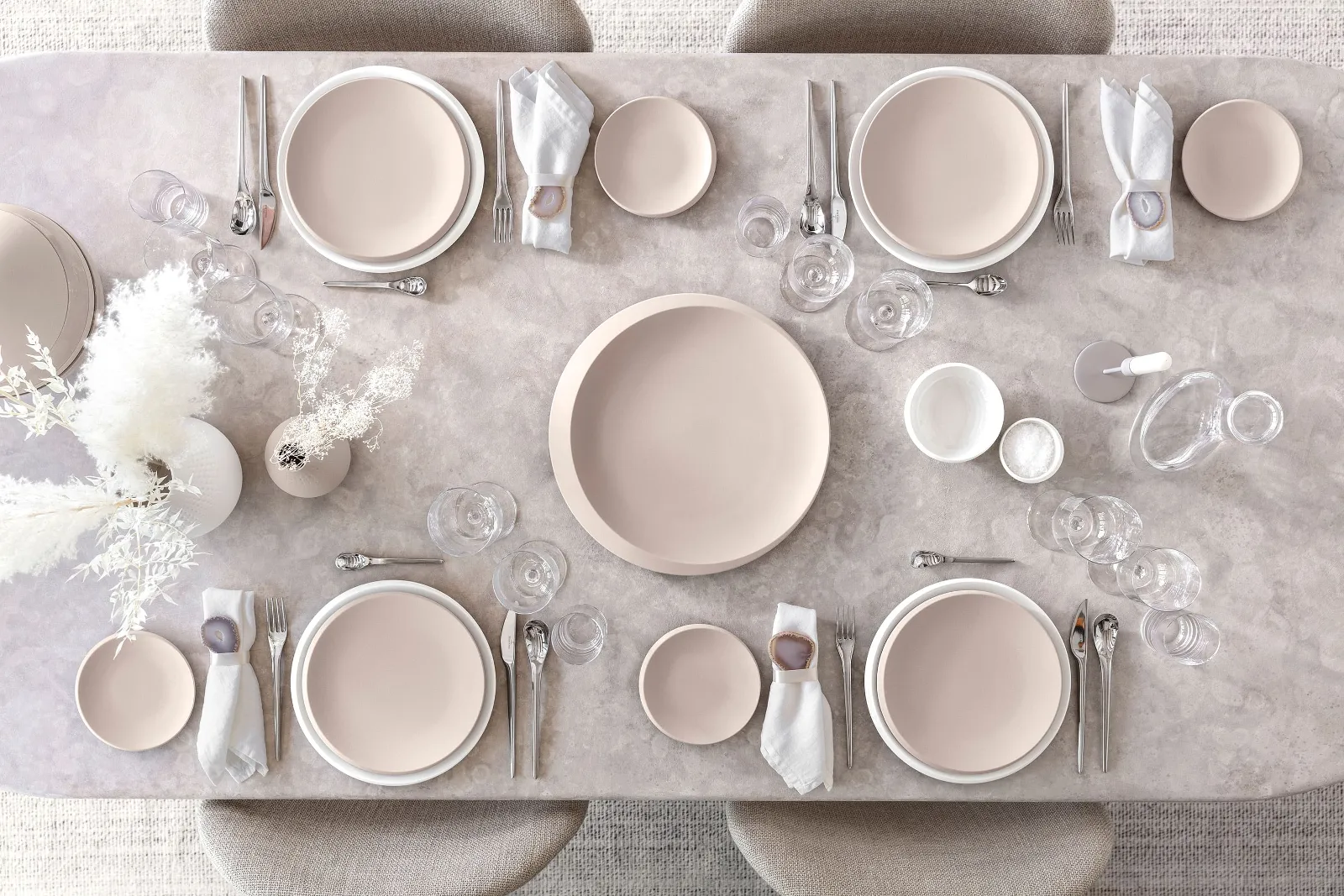 Et bord dekket med Villeroy & Boch NewMoon-tallerkener i beige og hvitt samt bestikk og glass.