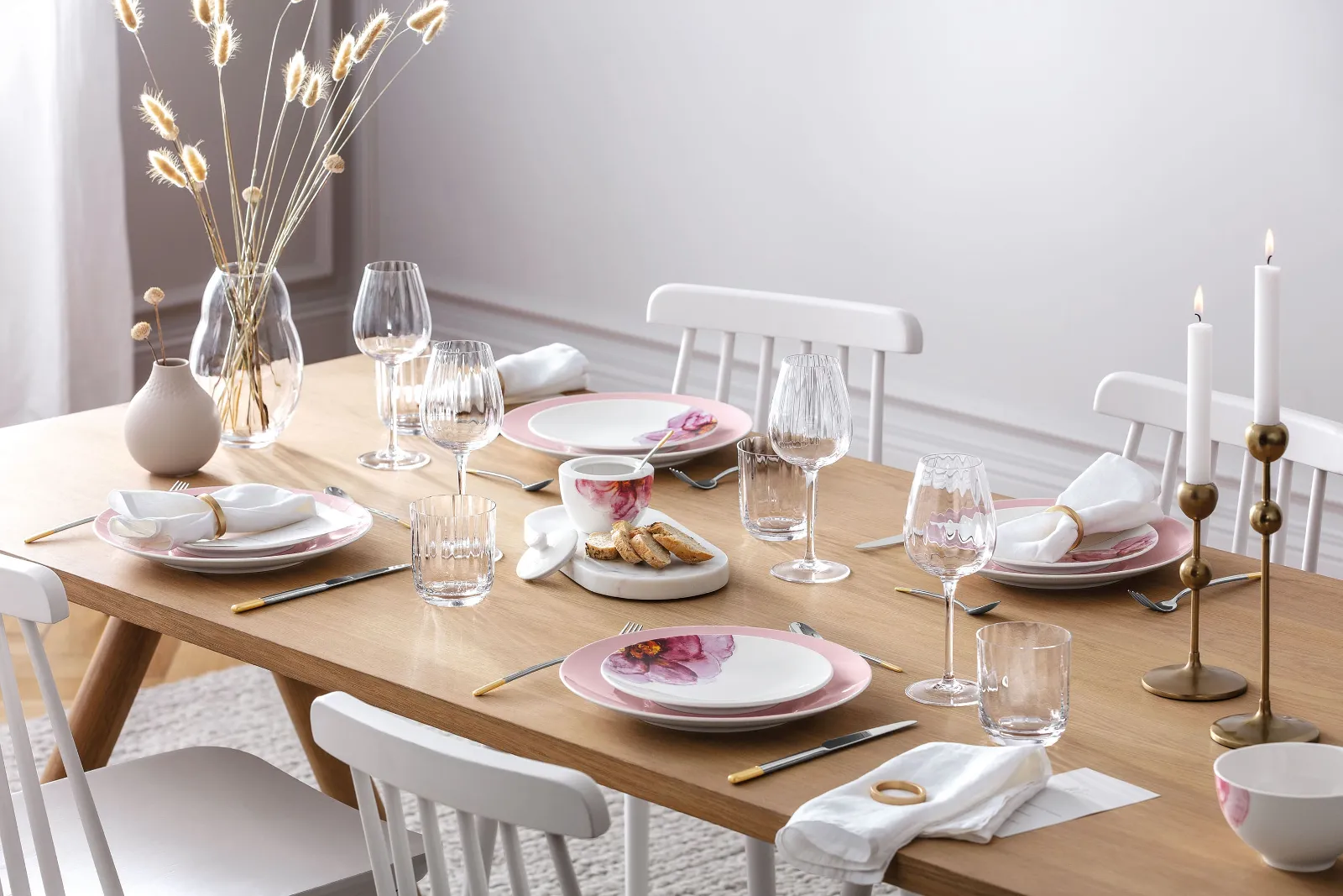 An elegant dining table with modern Rose Garden dinnerware, decorative candles and a Rose Garden vase with pampas grass.