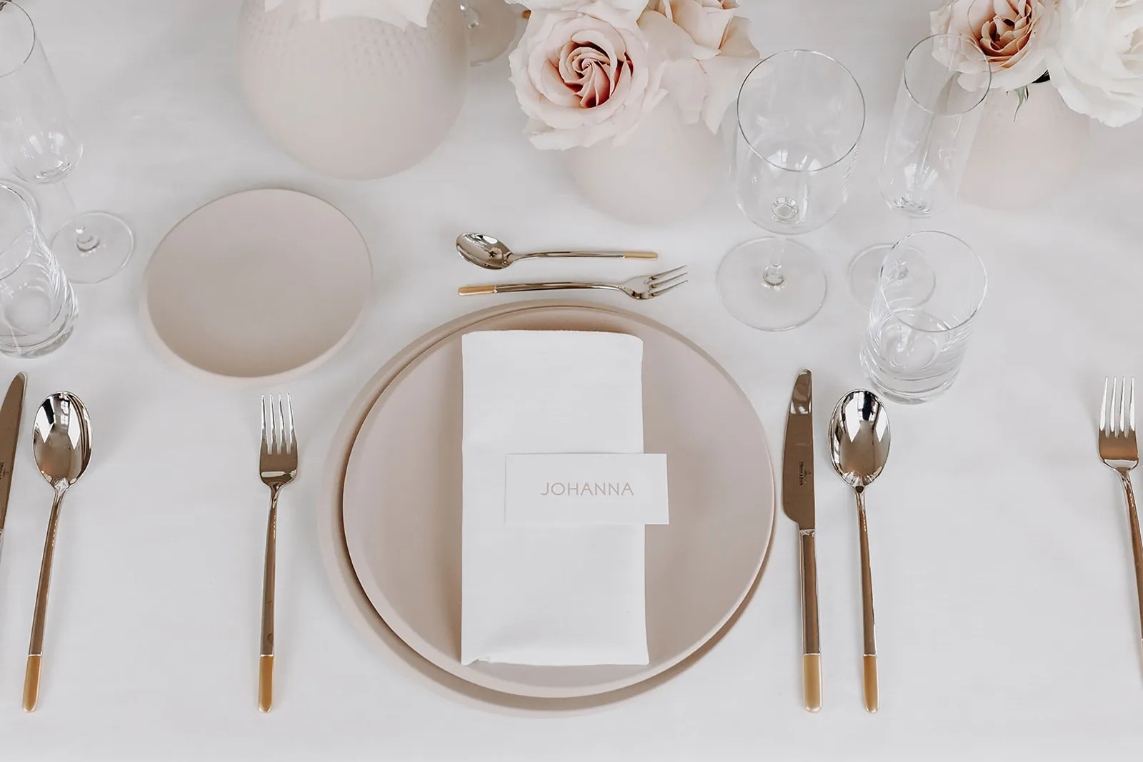 A festive table setting with white and beige NewMoon plates, Ella cutlery and NewMoon glasses.