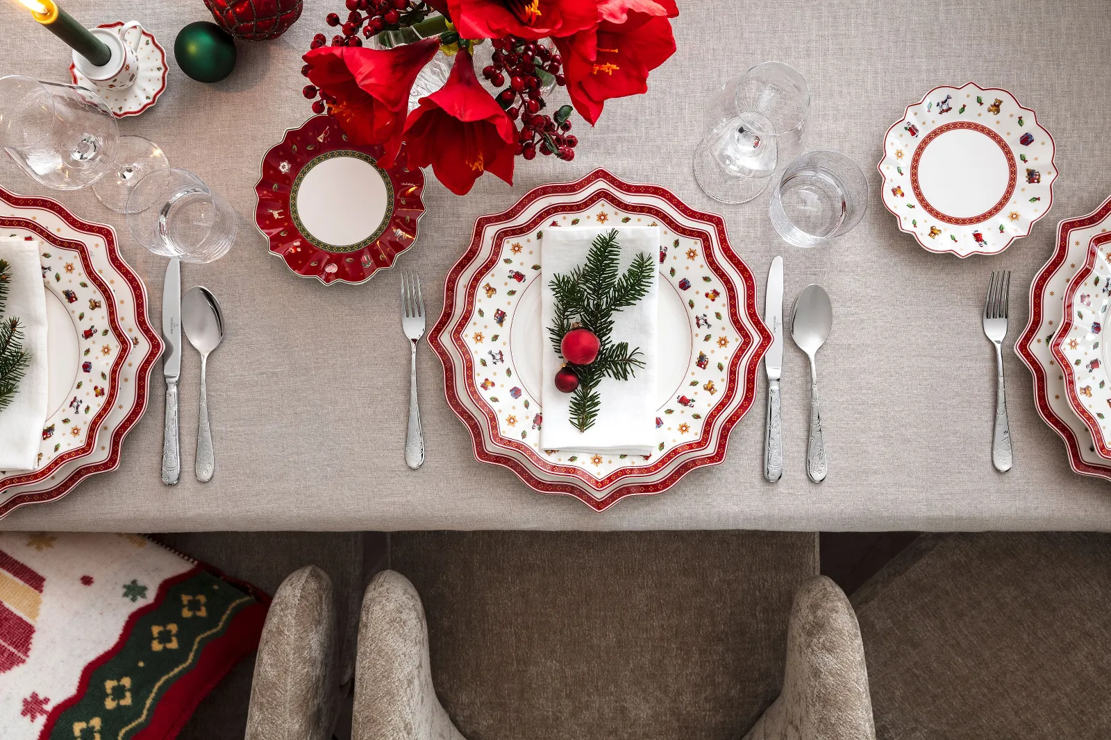 A festive table setting with Toy’s Delight plates, flatware, and glasses, neatly arranged on a beige tablecloth.