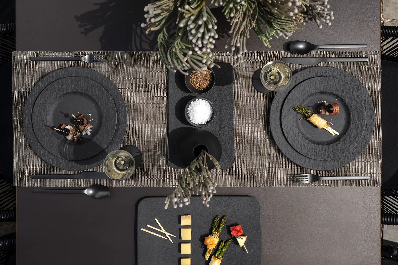 A modern dining table with two place settings, each with Manufacture plates, cutlery, napkins, starters and glasses.