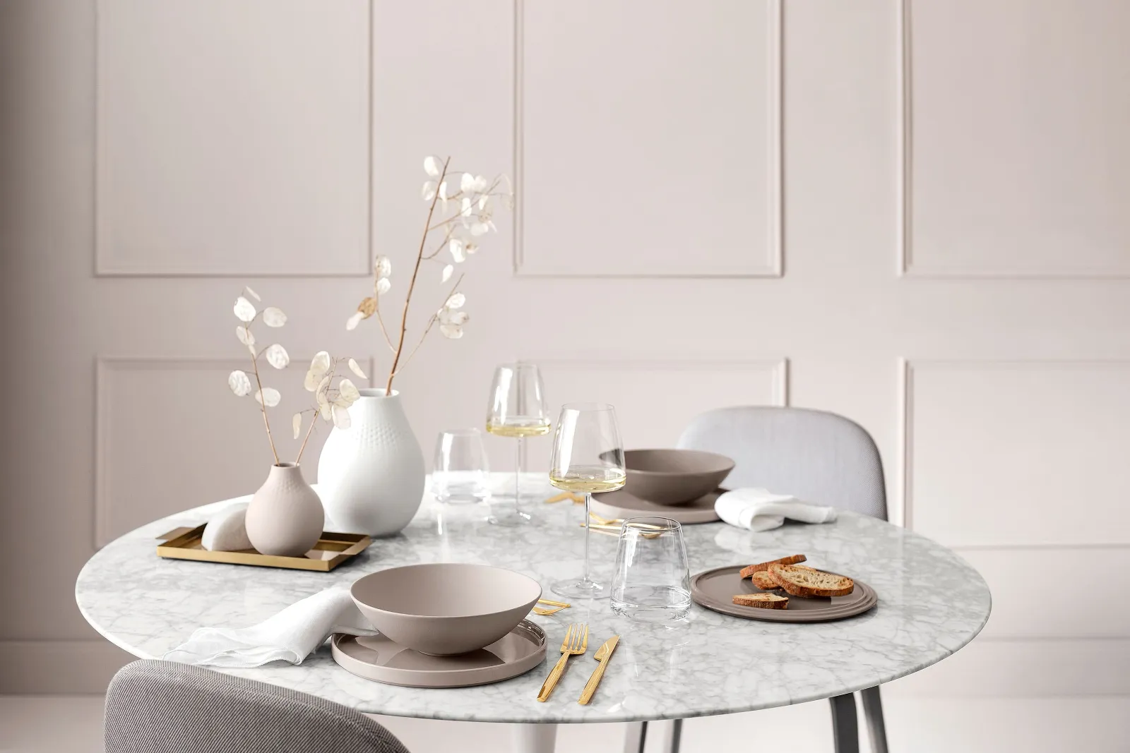 A dining table with a white table cloth and a vase of flowers, set with La Boule Pure Beige and MetroChic wine glasses.