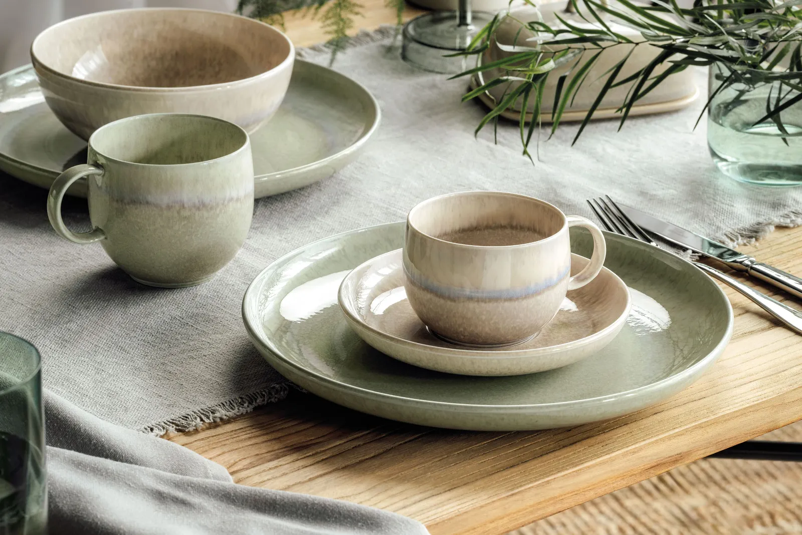 Rustic table decoration with Perlemor plates and cups in subtle earthy colours on a wooden table.