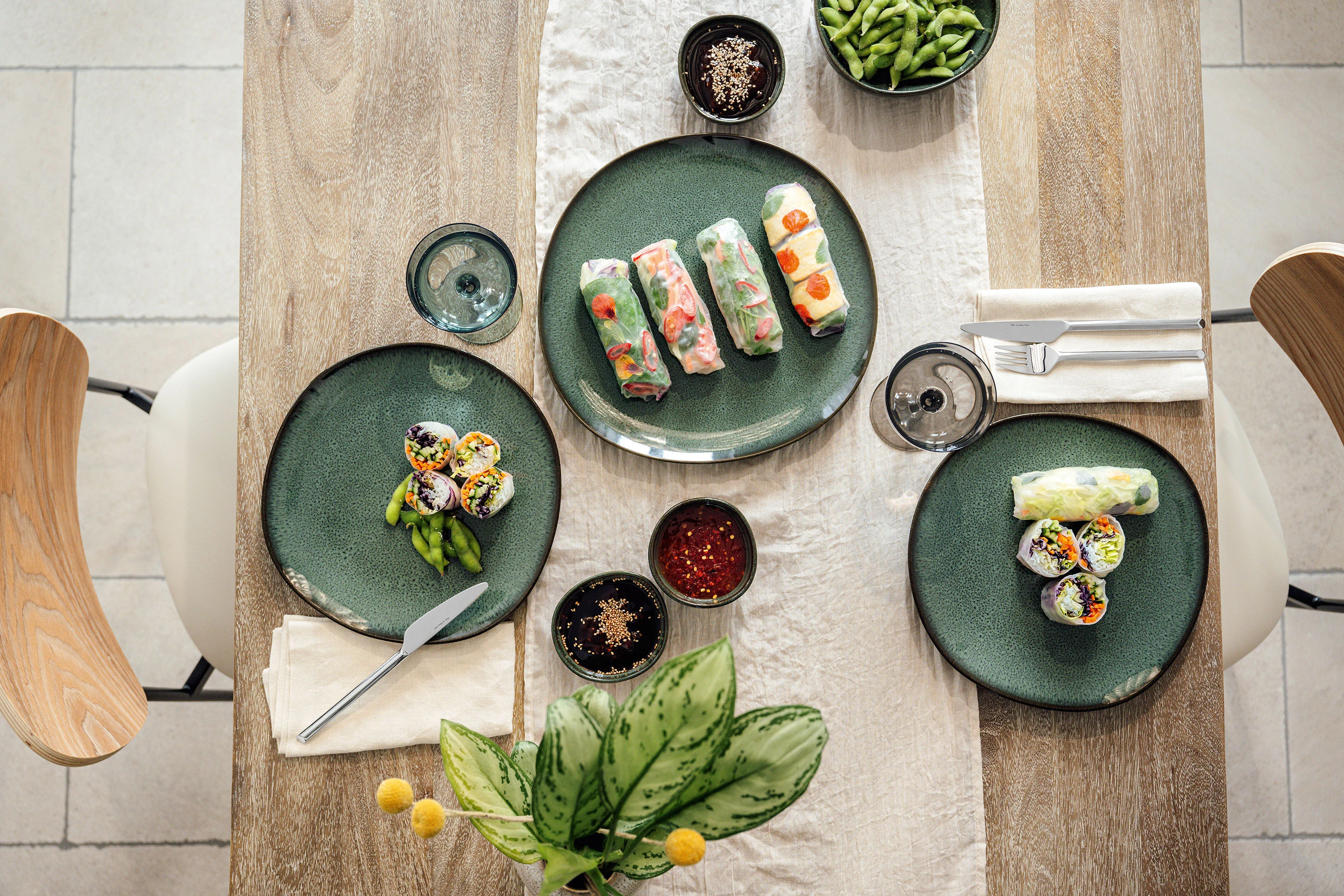 Villeroy & Boch Lave plate with summer rolls Flat, dark green stoneware plate Lave Vert with freshly prepared summer rolls, small dipping bowls, cutlery and glasses from the brand Like.