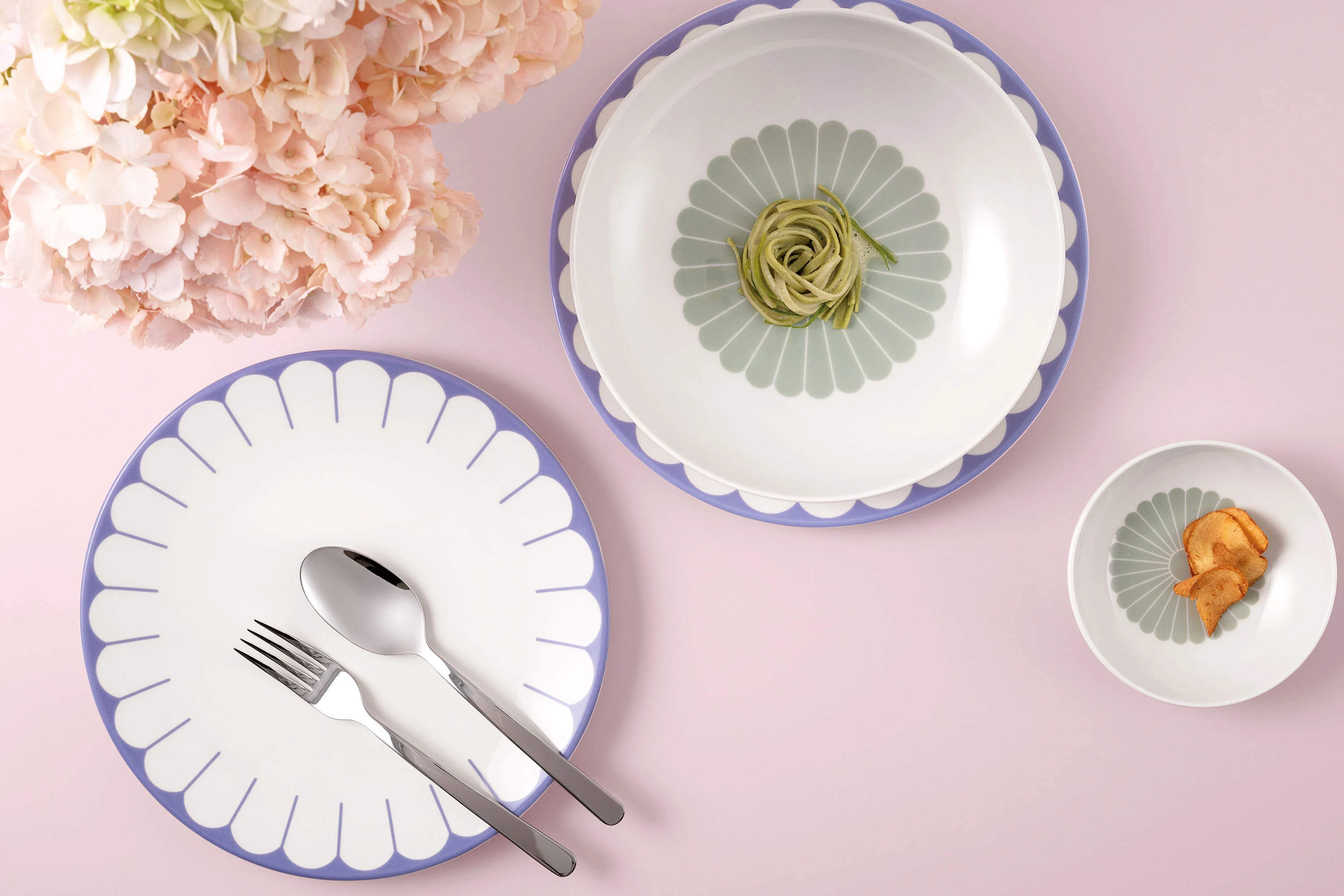 Plate, bowl and dish from the Fleur collection by Villeroy & Boch with food and pink flowers on a light pink background.