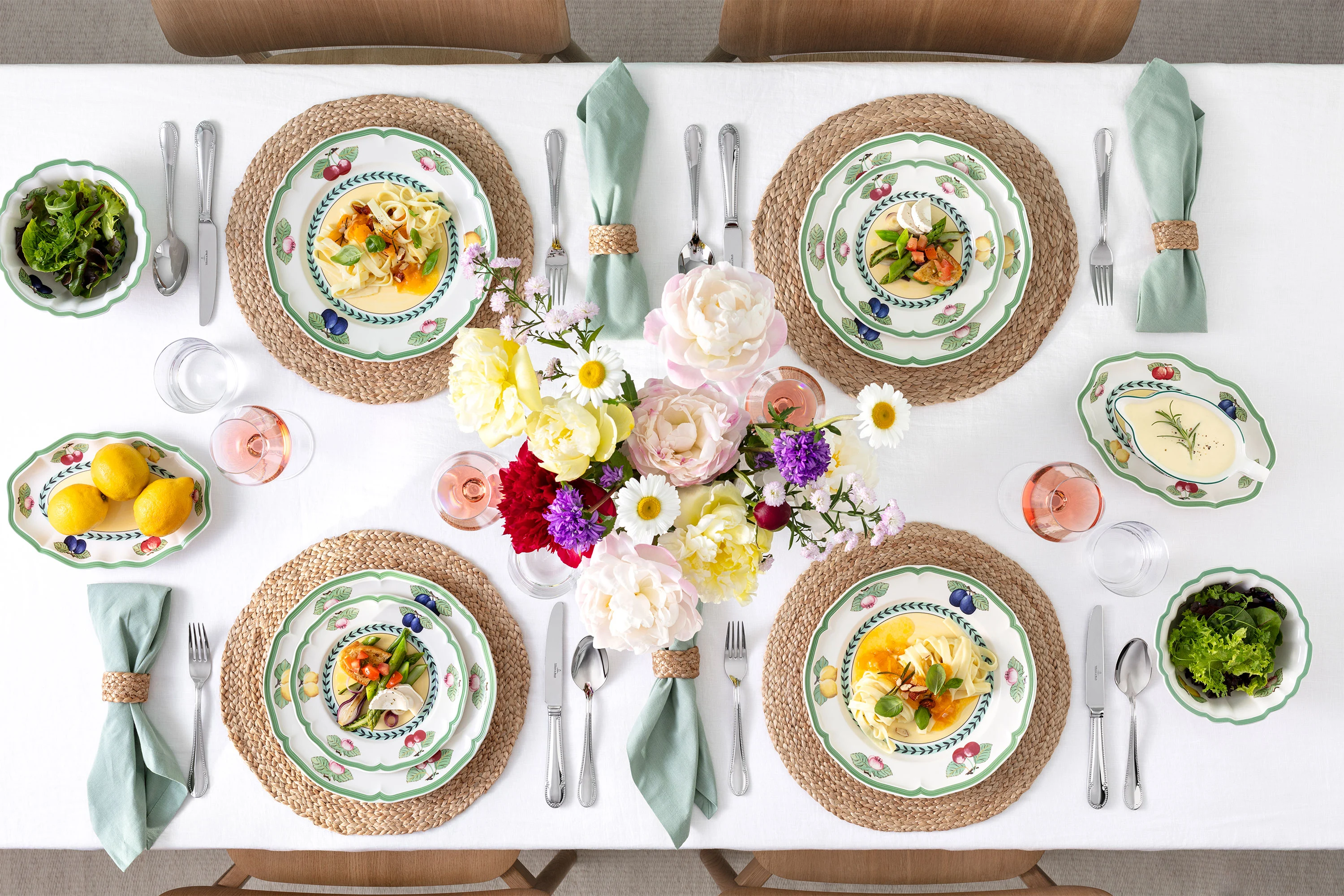 A table set with French Garden plates A table set for four with French Garden plates, linen napkins, salads, flowers in the centre and bowls of lemons and greenery