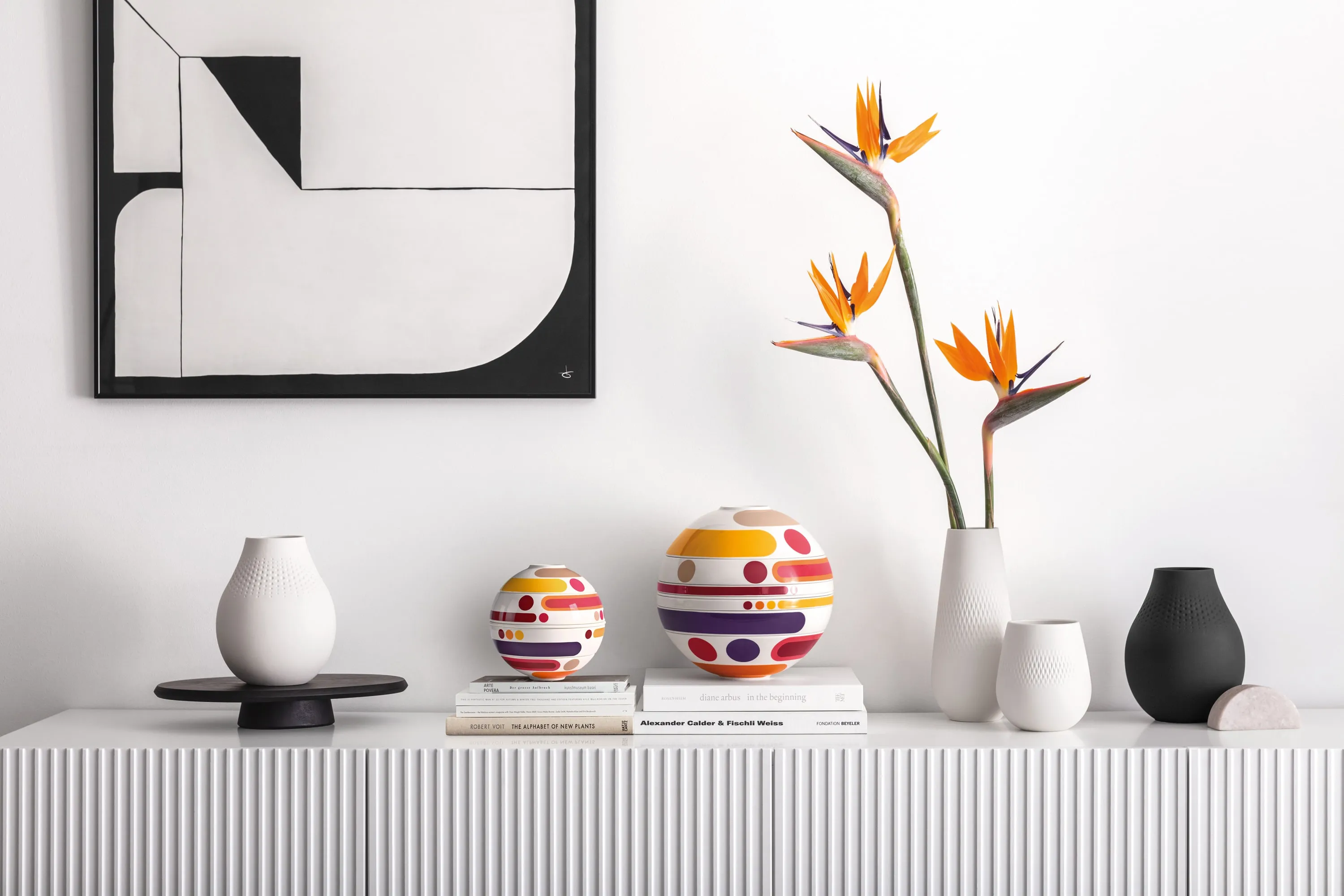 La Boule Miami decoratively staged A minimalist sideboard showcases the modern La Boule Miami, vases, bird of paradise flowers, and stacked books under abstract wall art.