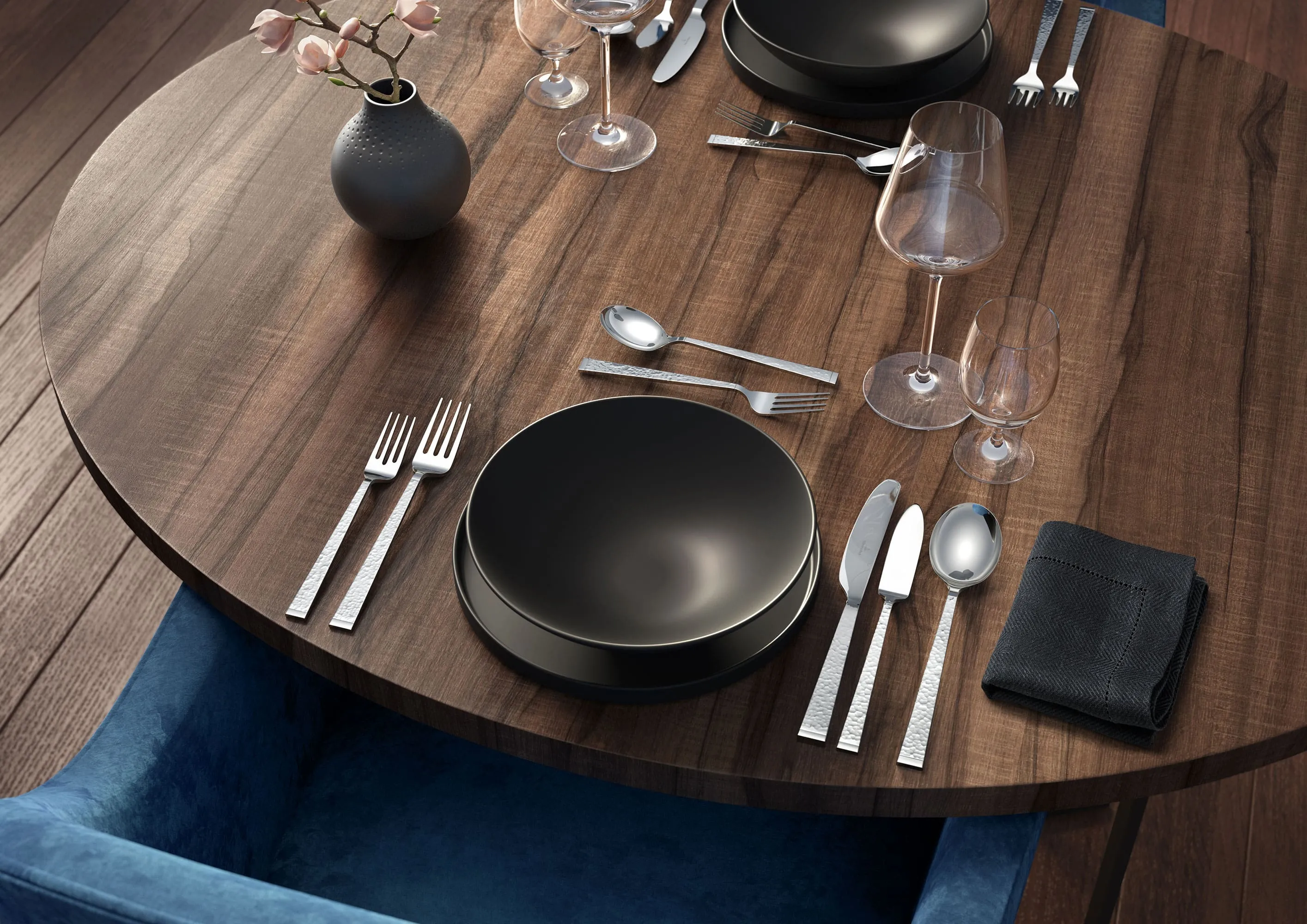 A wooden dining table set with Villeroy & Boch Blacksmith cutlery, La Divina glasses and plates from the black La Boule.