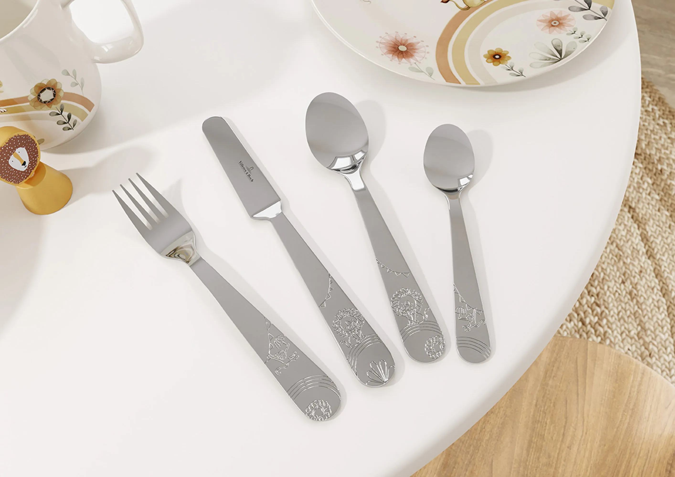 Un ensemble de couverts de table Boho Kids avec une assiette en porcelaine ornée du même décor Un ensemble de couverts de table en acier inoxydable pour enfants de la collection Boho Kids avec un motif ludique, bien rangés à côté d’une assiette en porcelaine avec un motif animalier plein de fantaisie.
