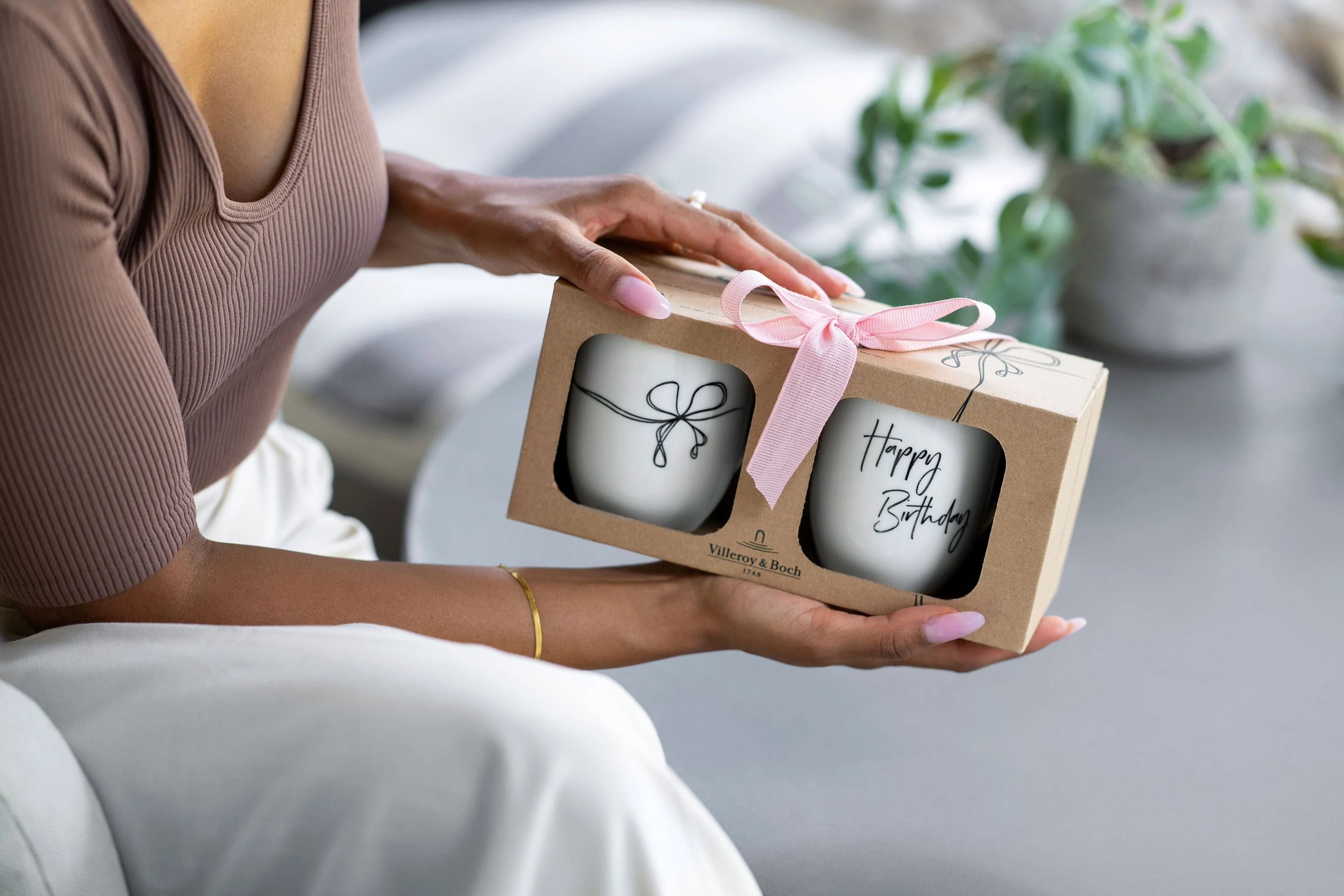‘Happy Birthday' mug in a gift box with a bow Person holding a gift box with a pink bow containing two 'Happy Birthday' Statement mugs.
