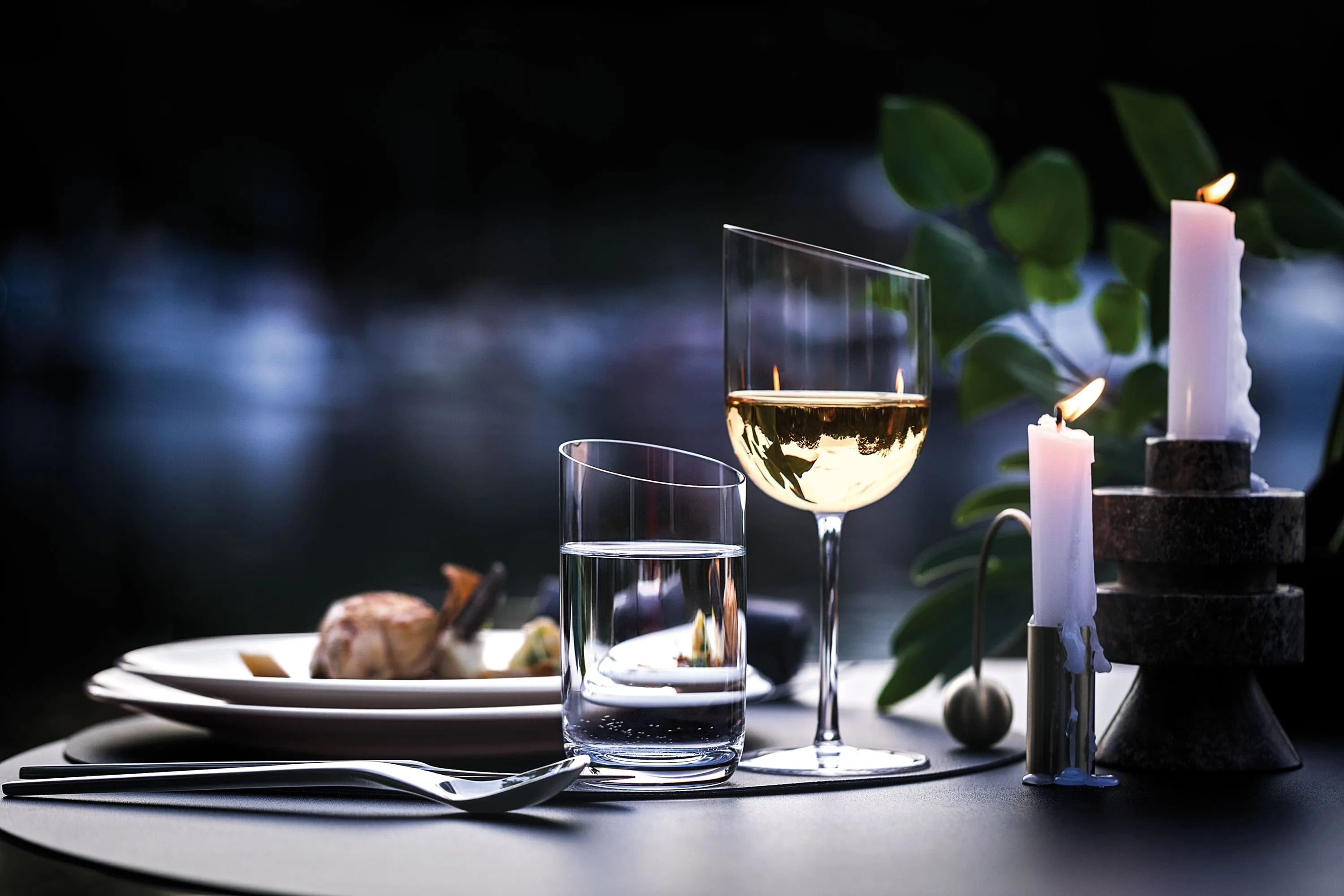 Des verres NewMoon à la lumière du soir et des bougies Des verres NewMoon contenant du vin et une bougie sur un ponton au crépuscule.