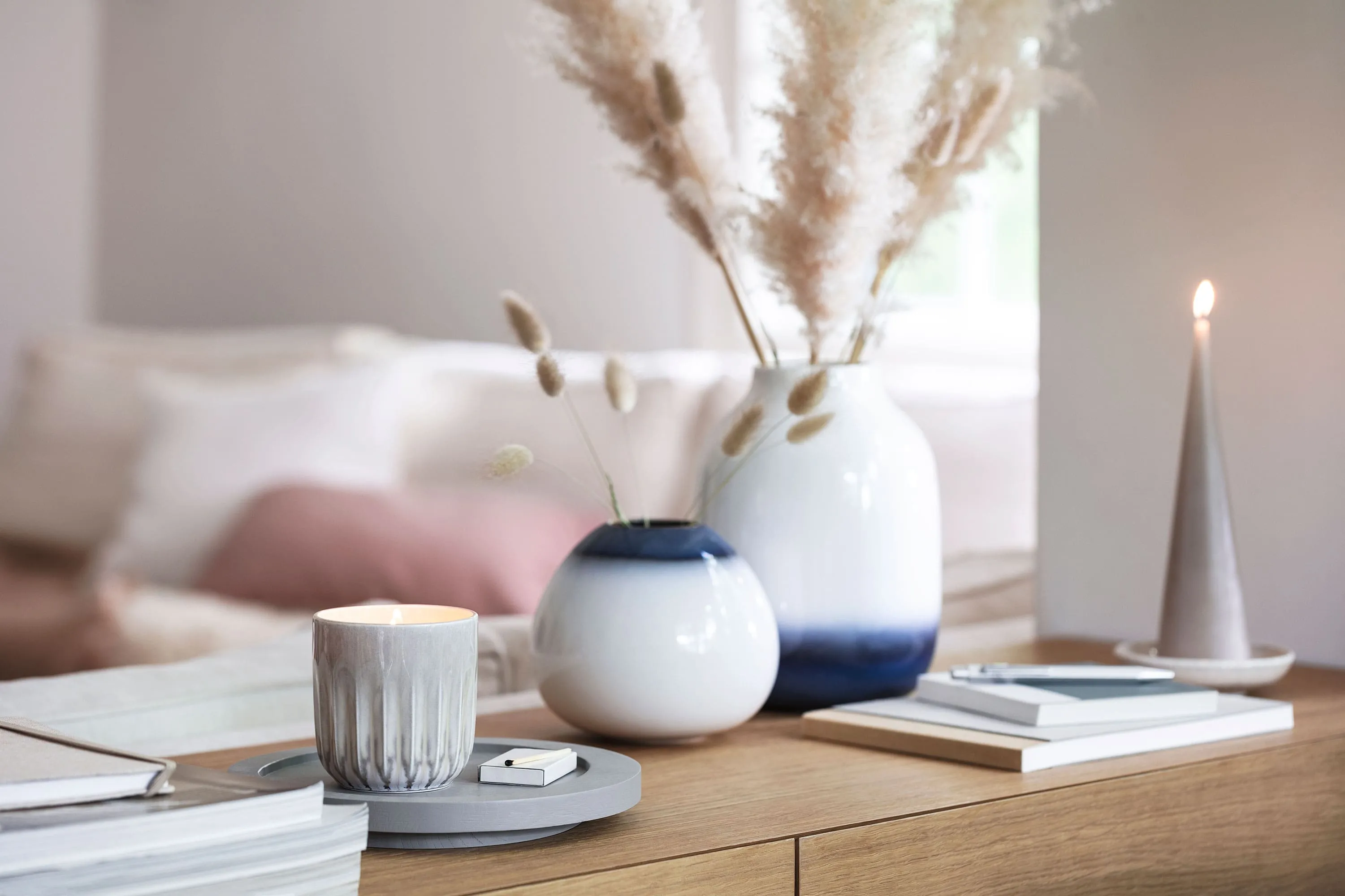 Vases Lave bleu et blanc avec une bougie parfumée Perlemor Un salon avec des vases Lave blanc et bleu, des livres et une bougie parfumée Perlemor.
