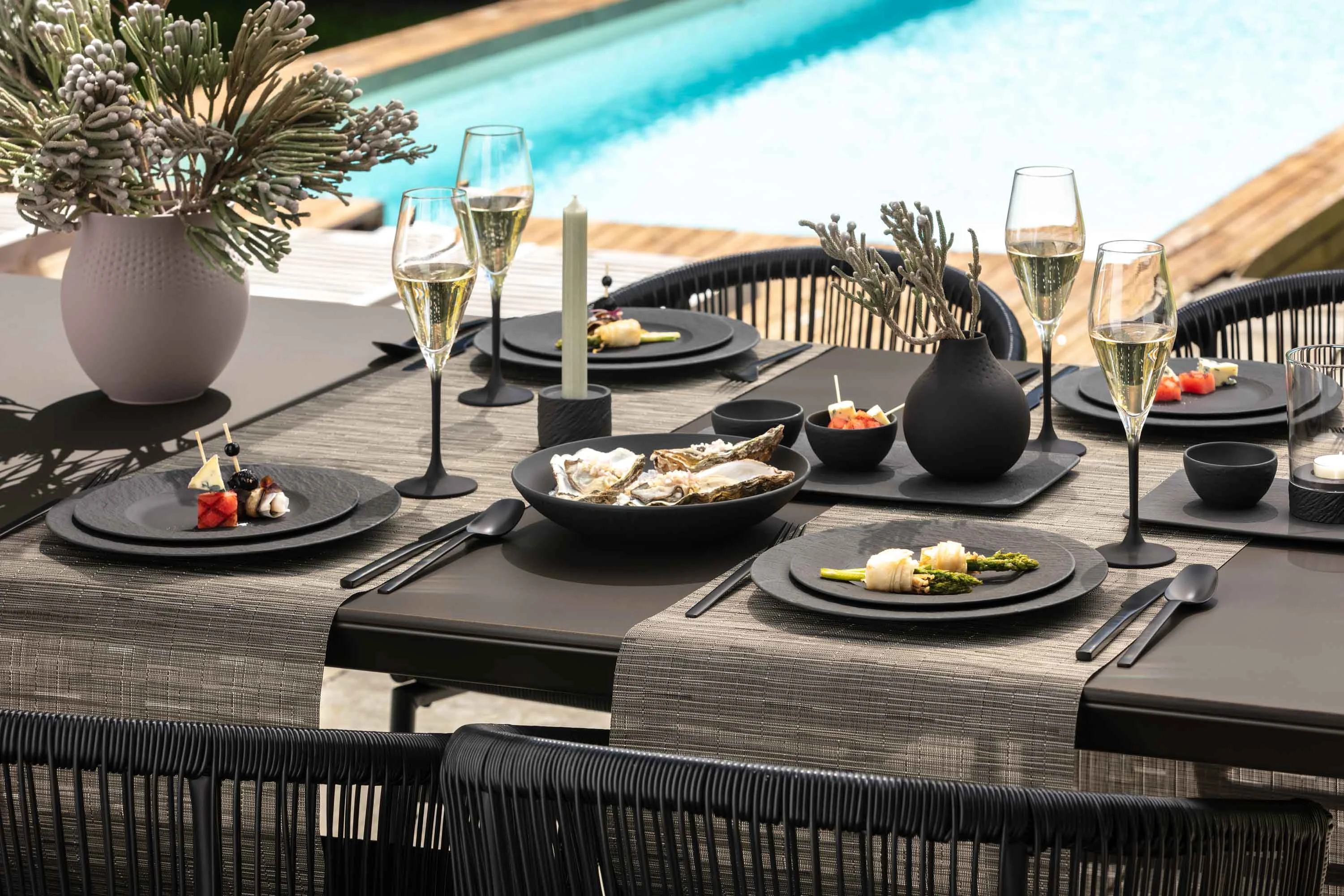 Elegant outdoor dining area with black Manufacture crockery and glasses Elegant outdoor dining area with black crockery and glasses from the Manufacture collection beside a swimming pool.