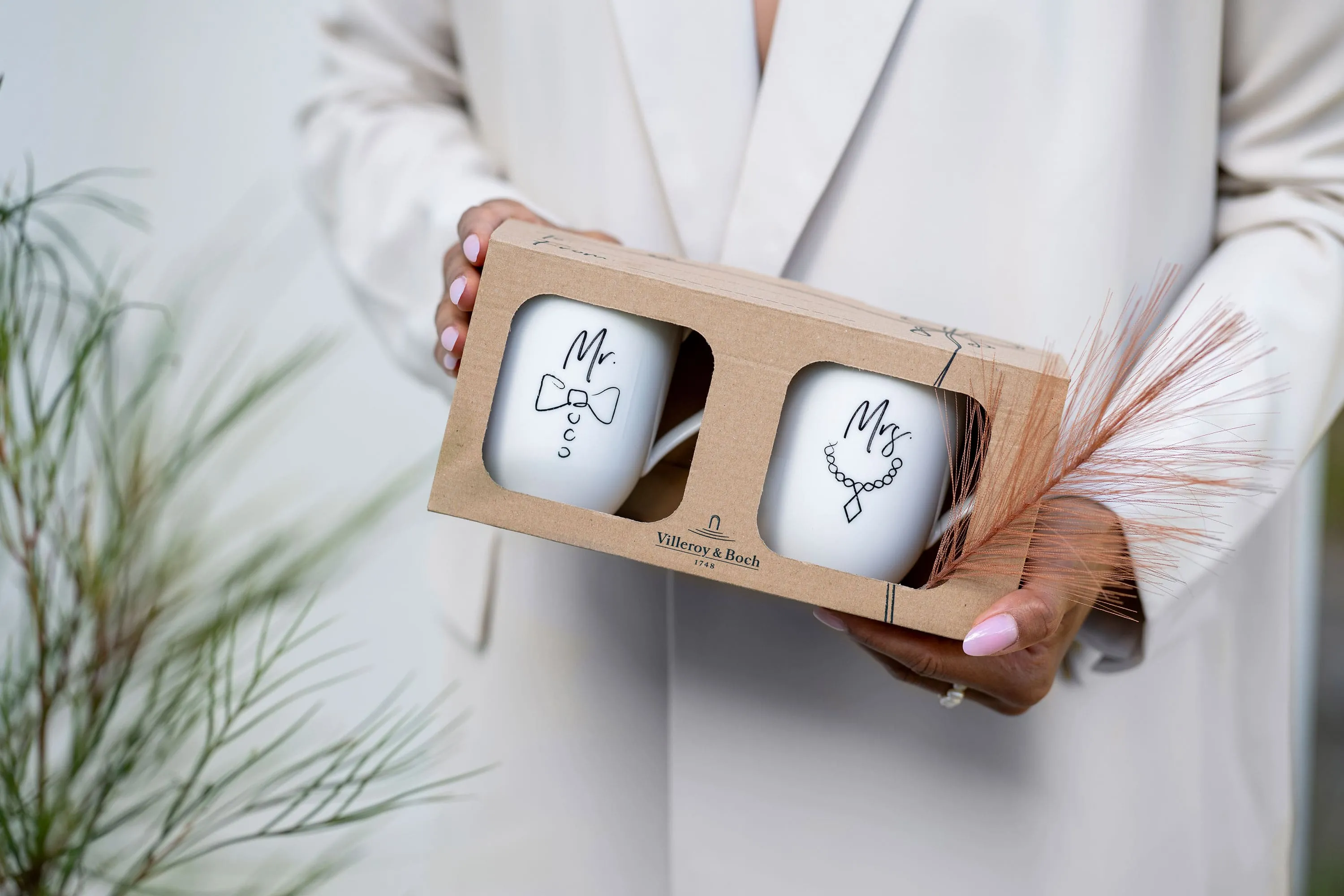 Une personne tient dans sa main une boîte cadeau contenant deux tasses Statement. Une personne tient dans sa main une boîte cadeau contenant deux tasses Statement portant l’inscription « Mr. » et « Mrs. ».