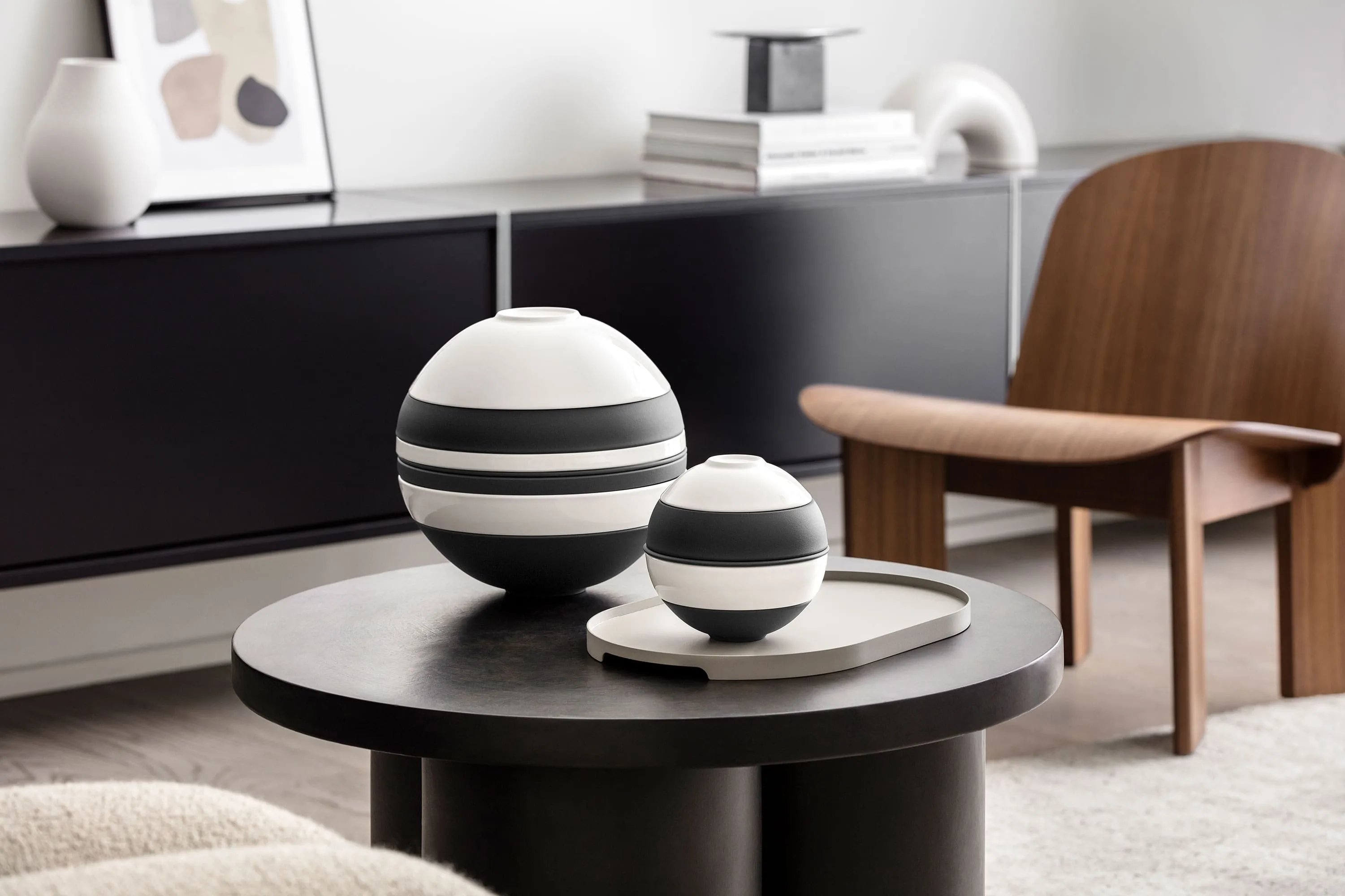 Un salon moderne avec La Boule et La petite Boule sur une table ronde foncée. Un salon moderne avec un modèle La Boule noir et blanc de Villeroy & Boch à côté de La petite Boule en noir et blanc sur une table ronde foncée.